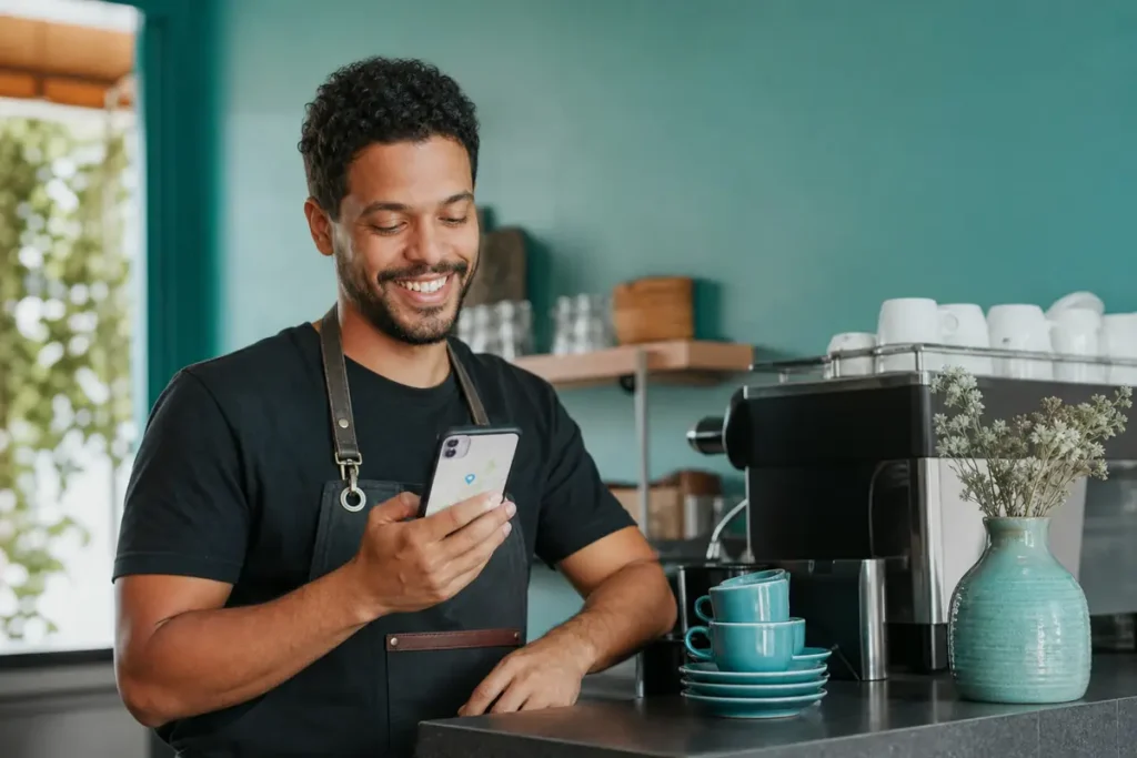 Dono de cafeteria conferindo no celular o perfil gratuito da empresa no Google